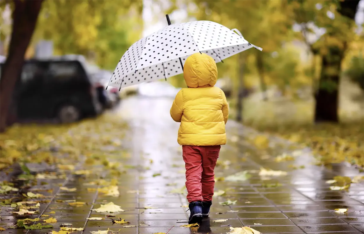 Little girl with umbrella walking in the rain